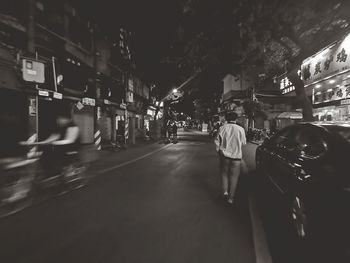 Rear view of people on illuminated street at night
