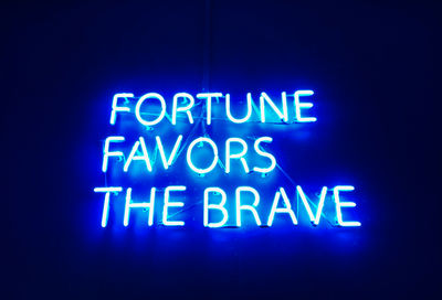 Close-up of neon text on wall against black background