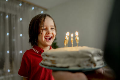 Cheerful cute boy with father holding birthday cake at home