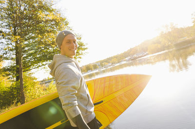 Man carrying paddle board on shore