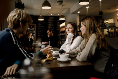 Teenage friends talking while sitting at table cafe