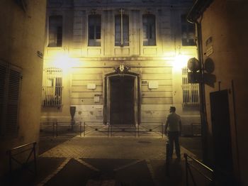 Man walking on illuminated street at night