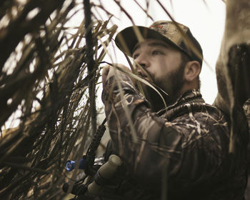 Low angle view of man blowing whistle while hunting on field