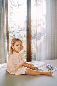 Portrait of cute girl sitting on bed at home
