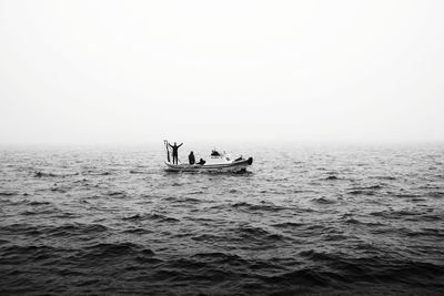 Men in sea against clear sky