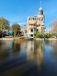 Buildings by river against clear sky