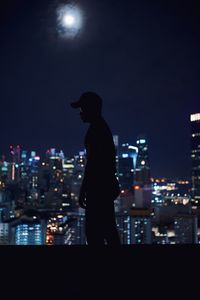 Man looking at illuminated city buildings at night