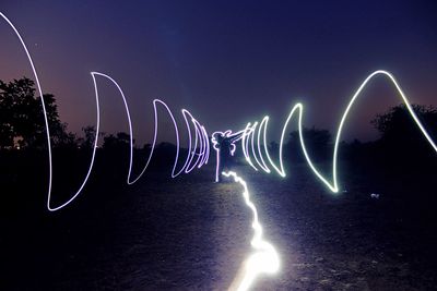 Light trails against clear blue sky at night