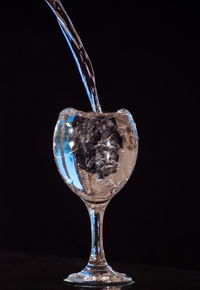 Close-up of wineglass on table against black background