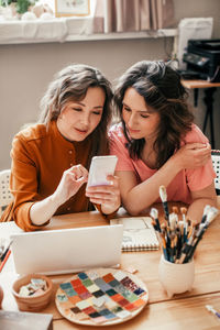 Two businesswomen discussing project presentation using a mobile phone