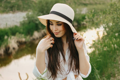 Smiling beautiful woman sitting by stream during sunset