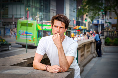 Portrait of young man standing by street in new york city, looking, thinking
