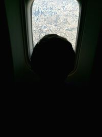 Rear view of boy looking through airplane window