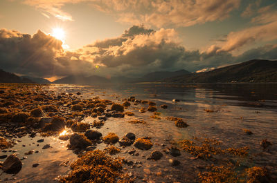 The sun is shining through the clouds on a lake in the scottish highlands