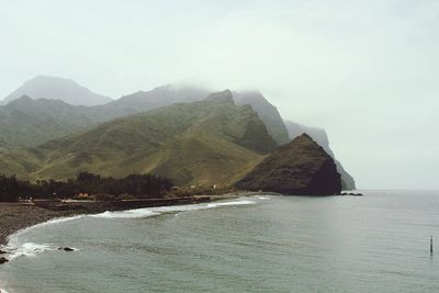 Scenic view of sea by mountains against sky