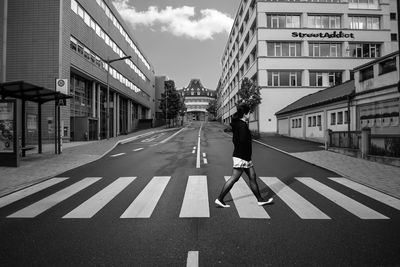 Man walking on road along buildings