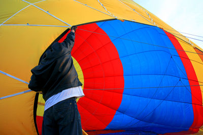 Man holding multi colored hot air balloon against sky