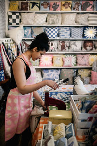 Side view of woman punching on textile while working in shop