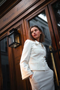 Portrait of young woman standing against wall