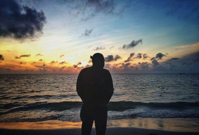 Silhouette man looking at sea against sky during sunset