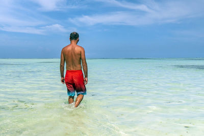 Rear view of shirtless man standing on beach