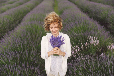 Woman holding lavender flowers on field