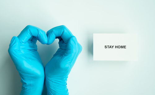 Human hand holding blue text against white wall