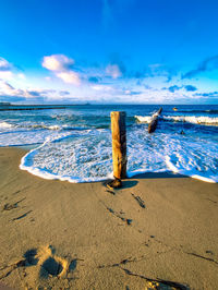 Driftwood on wooden post at beach against sky