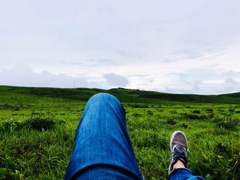Low section of person on field against sky