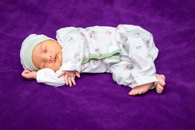 Newborn baby isolated sleeping in white cloth with purple background from different angle