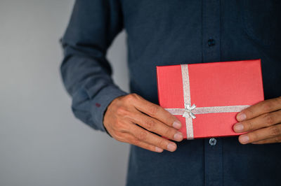 Midsection of man holding red box against white background