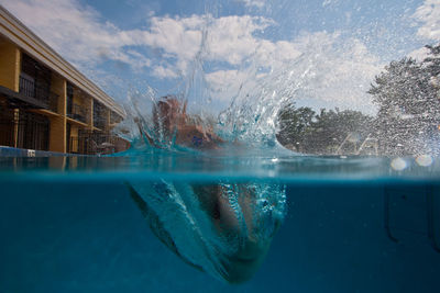 Water splashing in swimming pool against sky