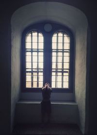 Child standing against window