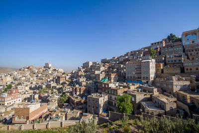 Buildings in city against clear blue sky