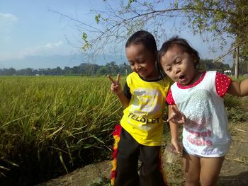 Siblings standing on field