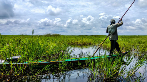 Rear view of man working at farm against sky