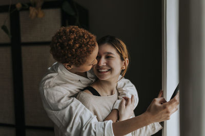 Happy non-binary couple embracing at home