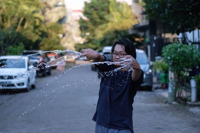 Man standing splashing water on street