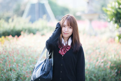 Portrait of smiling young woman standing against plants