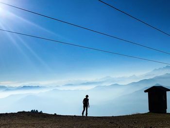 Man standing on mountain against blue sky