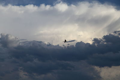 Low angle view of airplane flying against cloudy sky