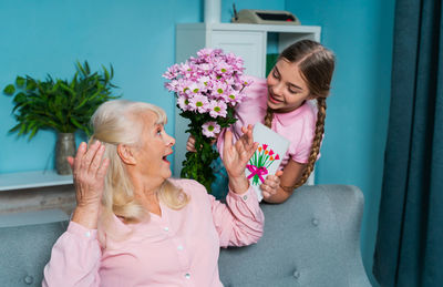 Happy girl giving bouquet to grandmother at home