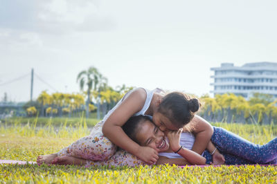 Cheerful sisters playing on grassy field at park