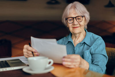 Senior businesswoman reading document at cafe