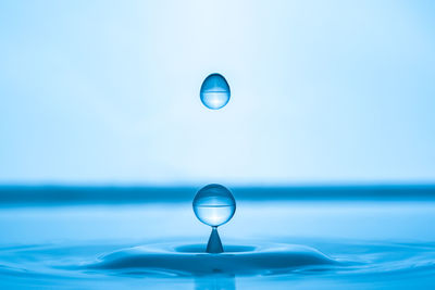 Water drop splashing into blue water surface. health and purity concept