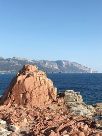 Scenic view of sea and rocks against clear blue sky