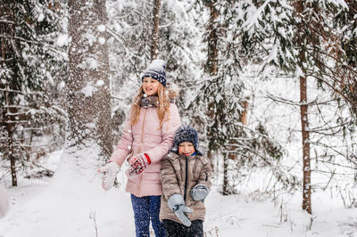 Happy boy with a girl sitting in the snow in the forest