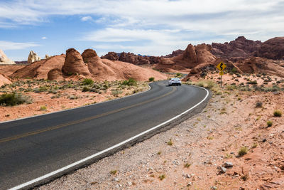 Road passing through desert against sky