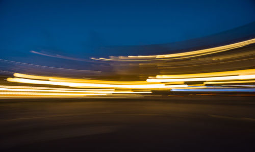 Light trails on road against sky at night