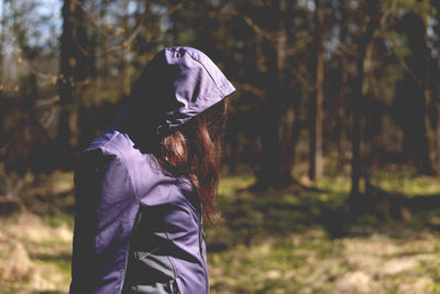 Side view of woman in hooded jacket walking on sunny day